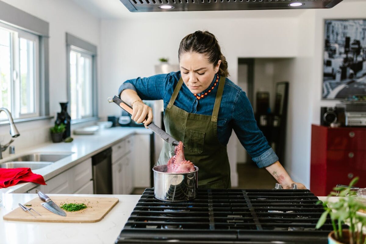 Chef cooks octopus on stove in a domestic kitchen setting, focusing on culinary skills.
